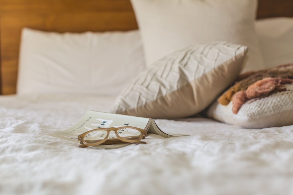 Briller ligger på seng med hvidt betræk