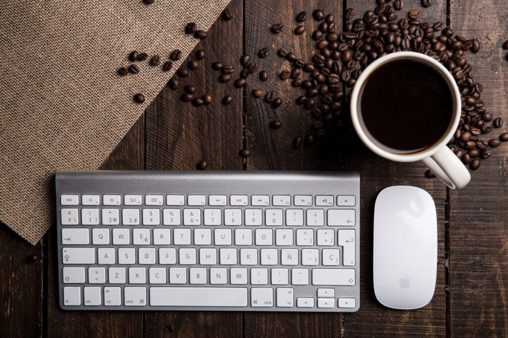 Tastatur og mus på bord med kaffebønner